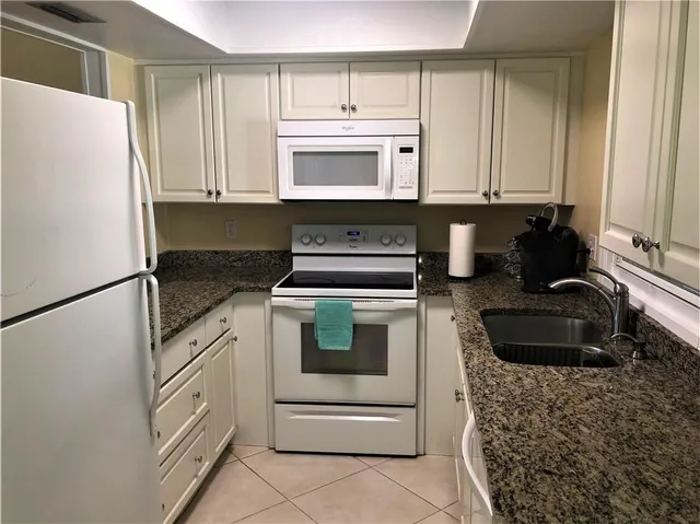 a kitchen with granite countertop white cabinets and white appliances