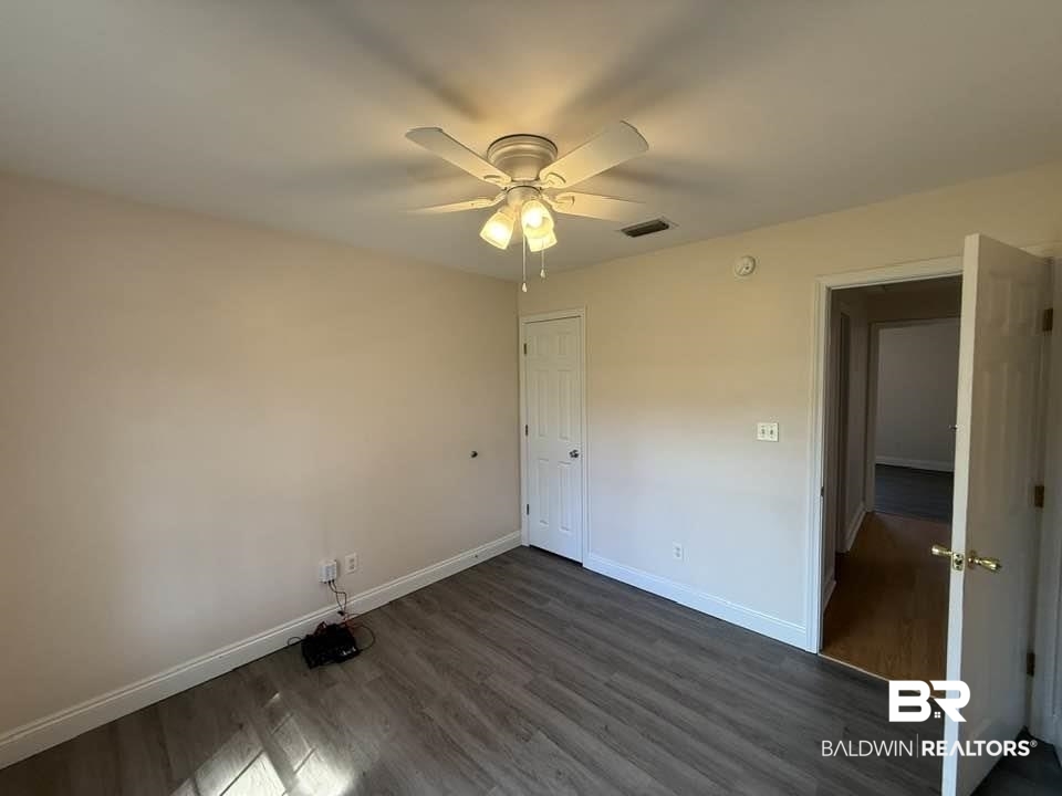 10428 South Side Loop Fairhope, AL 36532 - Photo 25 of 28 Unfurnished bedroom with dark wood-style floors, ceiling fan, visible vents, and baseboards