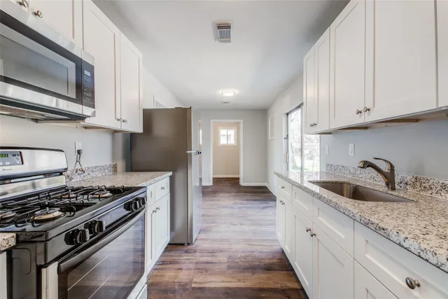 a kitchen with stainless steel appliances granite countertop a sink stove and refrigerator