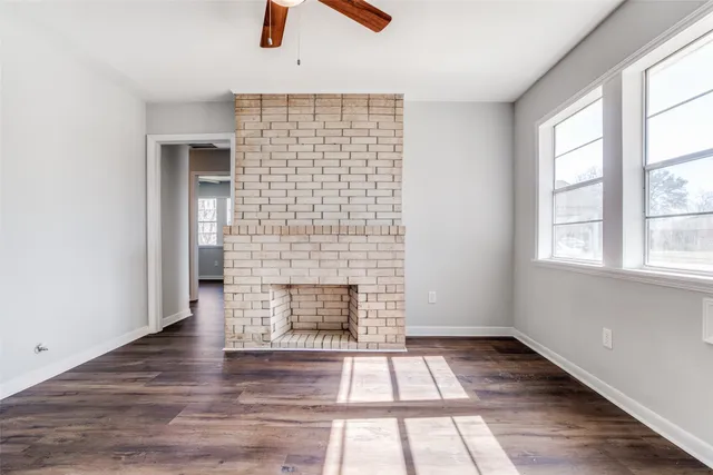an empty room with windows and fireplace