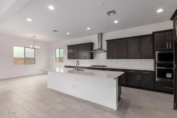a view of an empty room and kitchen with a sink wooden floor and a fireplace