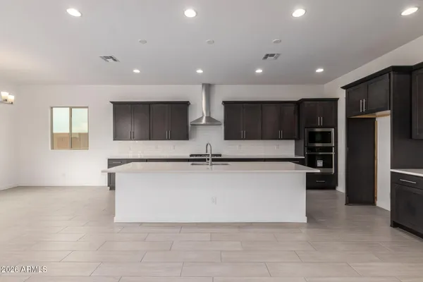 a large kitchen with stainless steel appliances a large counter top a stove and a sink