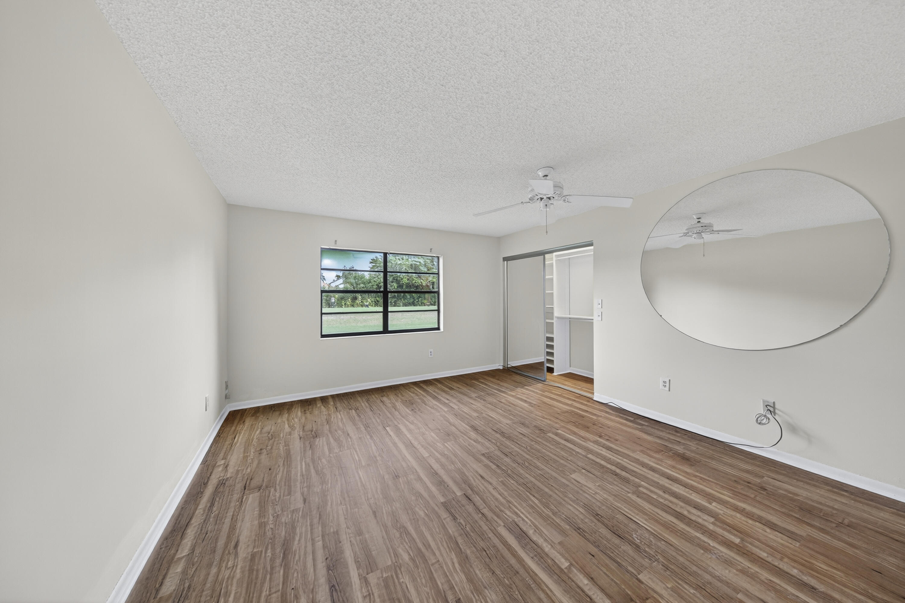 9187 Norte Lago, Unit 5I Boca Raton, FL 33428 - Photo 19 of 37 an empty room with wooden floor and windows