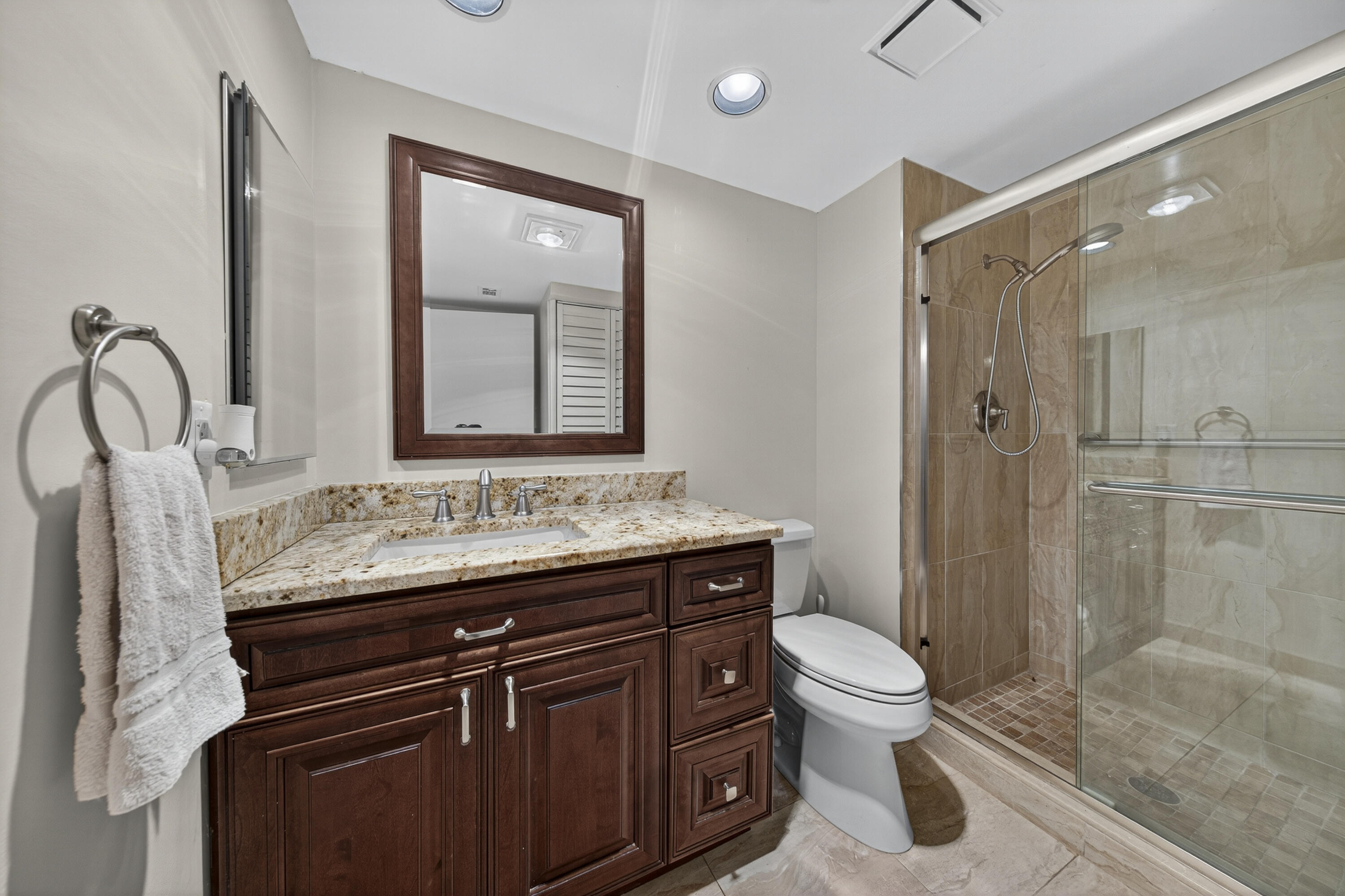9187 Norte Lago, Unit 5I Boca Raton, FL 33428 - Photo 29 of 37 a bathroom with a granite countertop sink toilet a mirror and shower