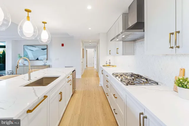 a kitchen with kitchen island granite countertop a stove a sink a oven and a dining table with wooden floor