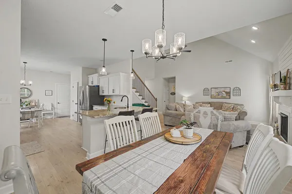 a view of a dining room and livingroom with furniture wooden floor a chandelier