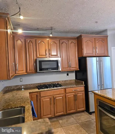 a kitchen with granite countertop a stove a sink and a refrigerator