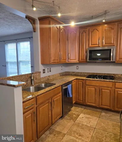 a kitchen with kitchen island granite countertop a sink stainless steel appliances and cabinets