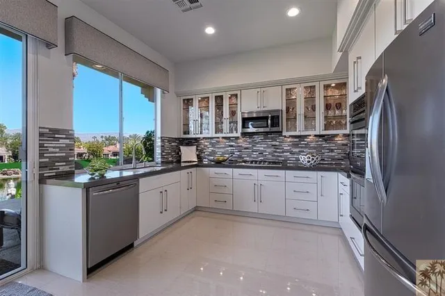 a kitchen with stainless steel appliances granite countertop a refrigerator a stove and a sink
