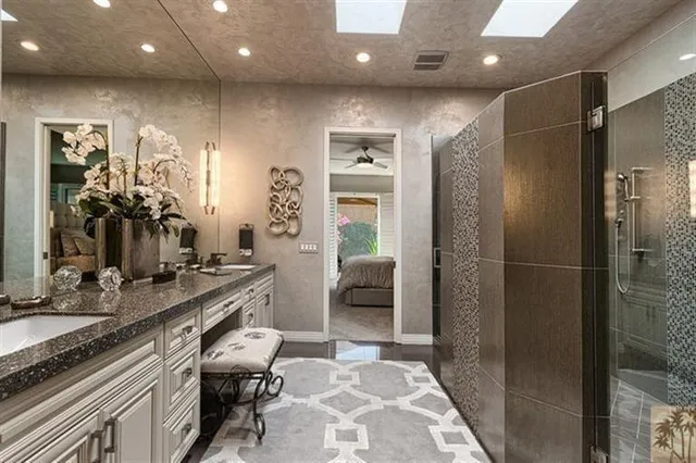 a bathroom with a granite countertop sink a toilet a mirror and shower