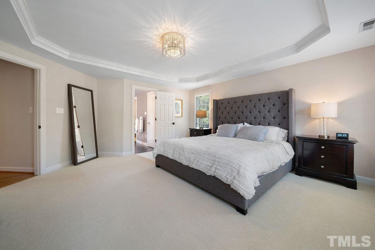 5533 Overleaf Court Raleigh, NC 27615 - Photo 15 of 32 a spacious bedroom with a bed and a chandelier