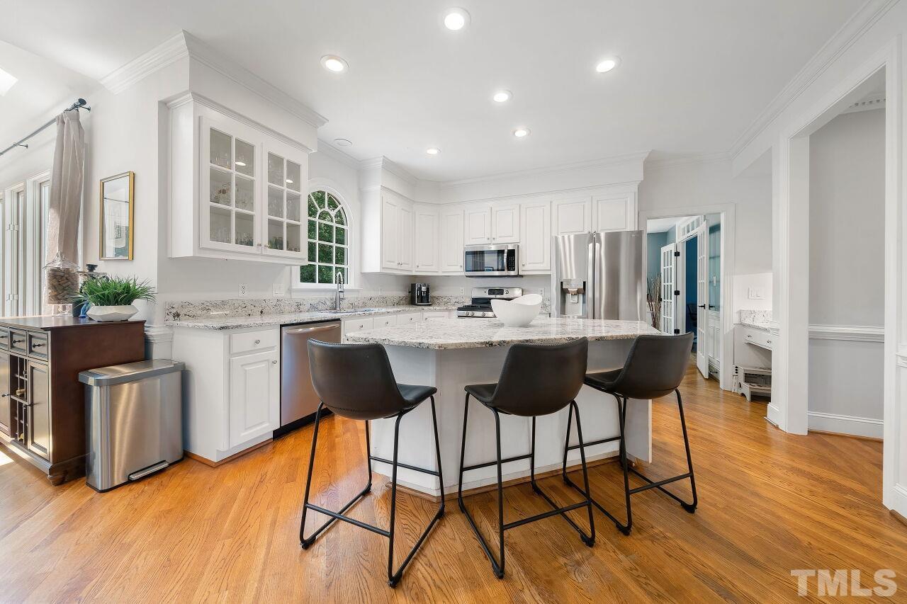 5533 Overleaf Court Raleigh, NC 27615 - Photo 7 of 32 a kitchen with stainless steel appliances kitchen island granite countertop a stove a refrigerator a sink a dining table and chairs