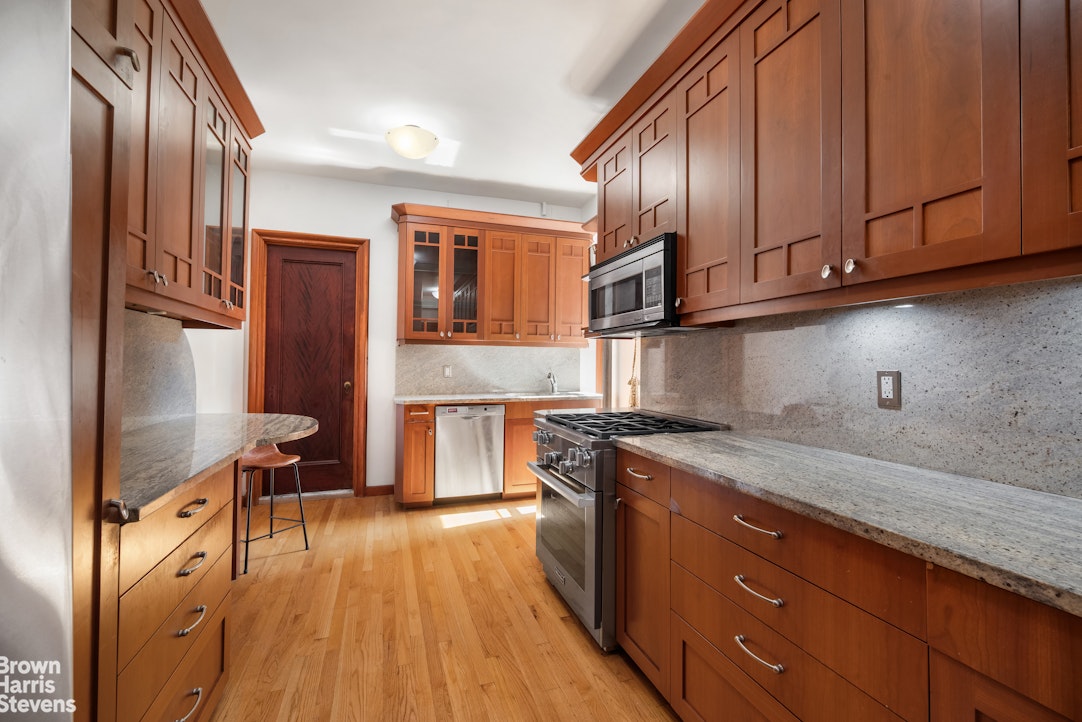 790 Riverside Drive, Unit 4J Manhattan, NY 10032 - Photo 10 of 11 a kitchen with stainless steel appliances granite countertop a stove a sink dishwasher and cabinets with wooden floor