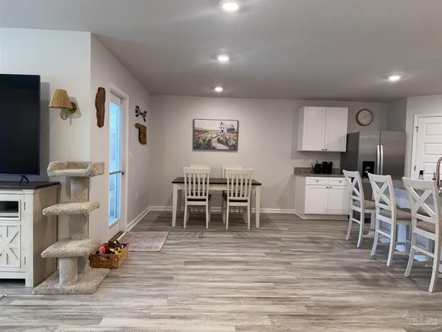 a kitchen with stainless steel appliances a stove a sink a microwave a refrigerator and white cabinets with wooden floor