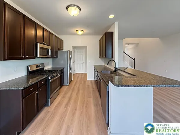a kitchen with stainless steel appliances granite countertop a sink stove and refrigerator