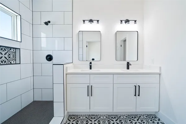 a bathroom with a double vanity sink a mirror and shower