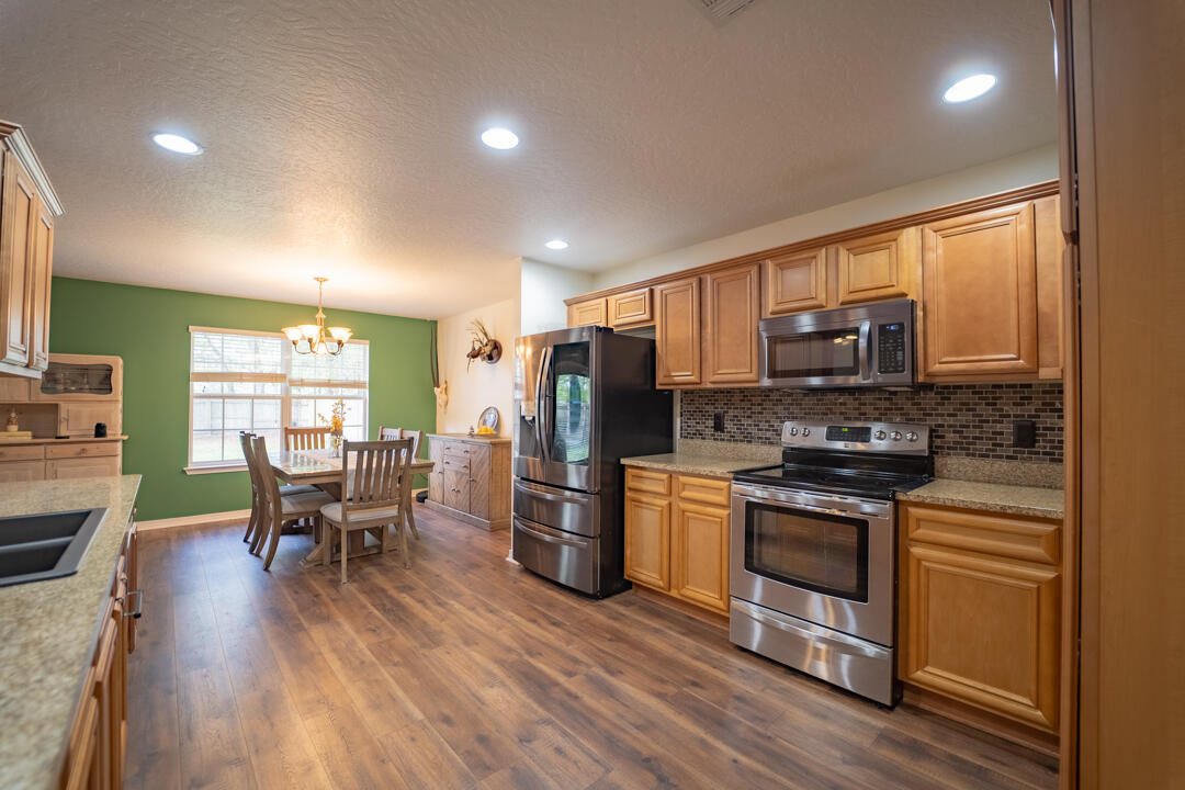 103 6th Avenue Shalimar, FL 32579 - Photo 7 of 23 a kitchen with stainless steel appliances granite countertop a stove top oven a sink dishwasher a dining table and chairs with wooden floor