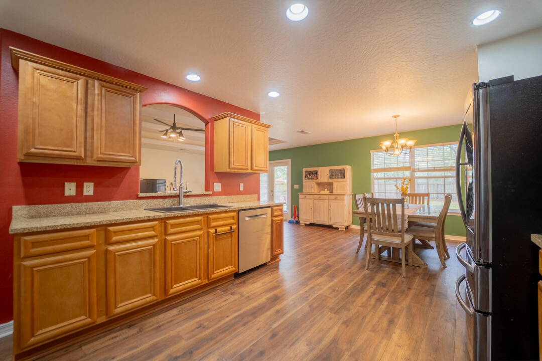 103 6th Avenue Shalimar, FL 32579 - Photo 8 of 23 a kitchen with stainless steel appliances granite countertop a refrigerator a sink dishwasher a dining table and chairs with wooden floor