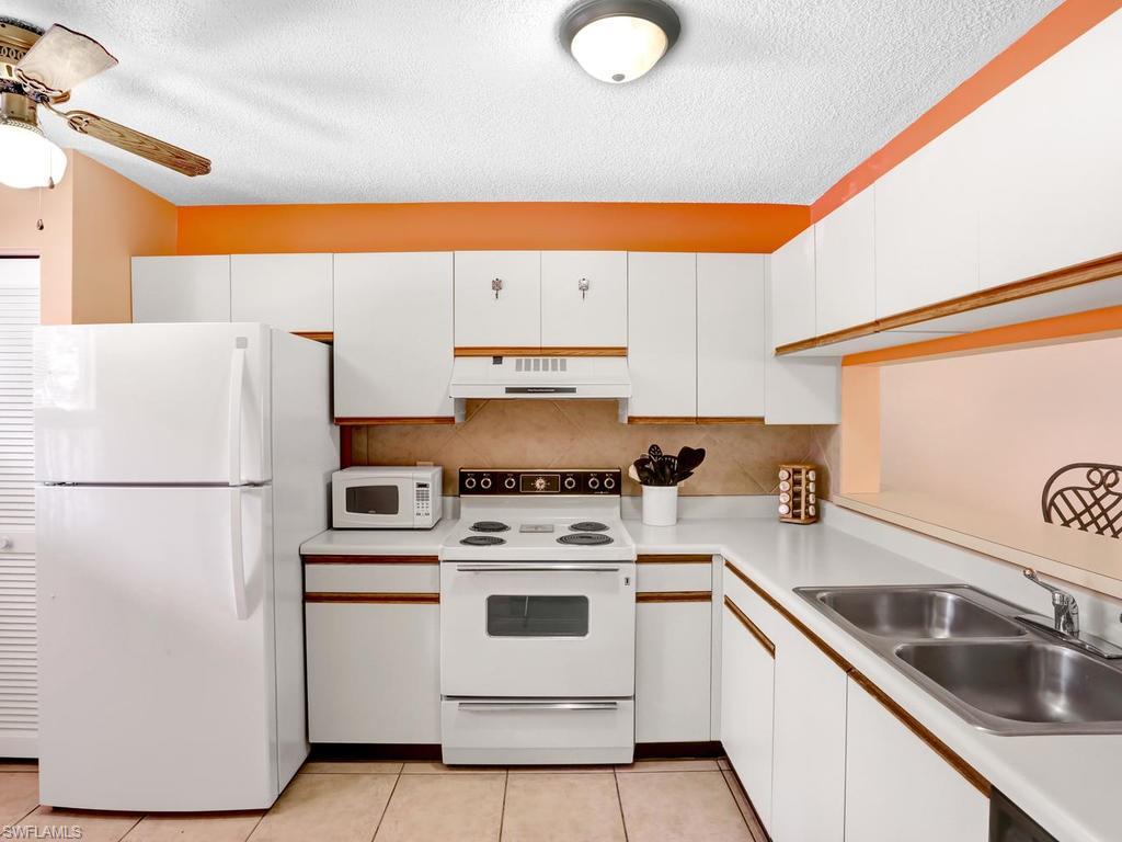 5675 Whitaker Road, Unit B102 Naples, FL 34112 - Photo 11 of 22 a kitchen with a white stove top oven and sink