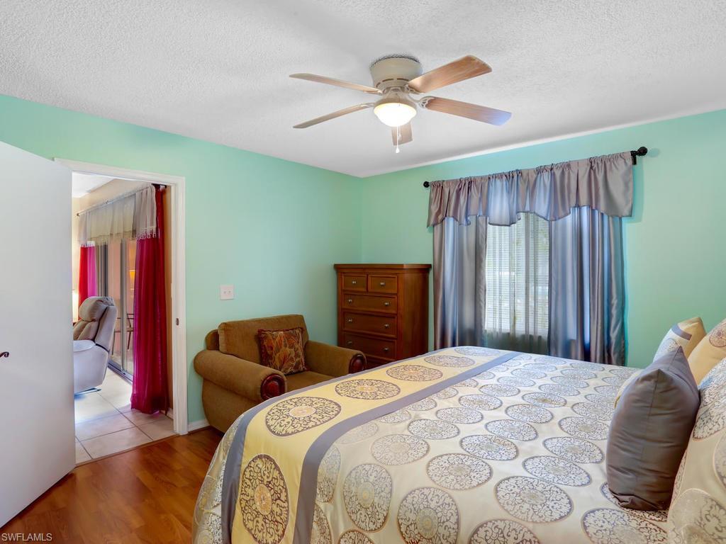 5675 Whitaker Road, Unit B102 Naples, FL 34112 - Photo 16 of 22 a bedroom with a bed and a chandelier
