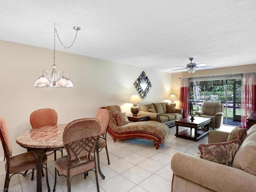 5675 Whitaker Road, Unit B102 Naples, FL 34112 - Photo 8 of 22 a living room with furniture a chandelier and a window