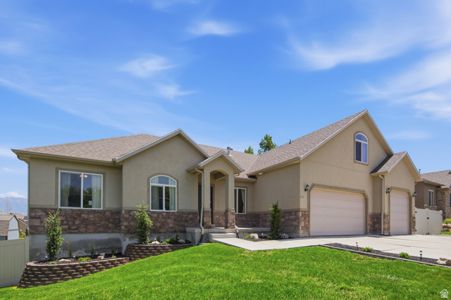 1252 Skyline Road Saratoga Springs, UT 84045 - Photo 6 of 51 Contemporary stucco home with a stone facade, featuring a multi-car garage, arched entry, and established landscaping