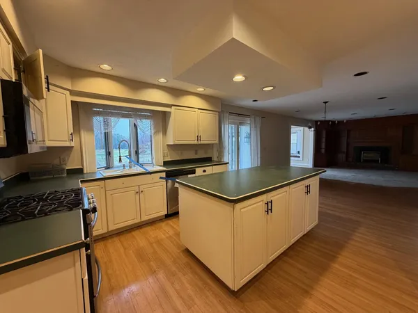 a kitchen with stainless steel appliances granite countertop a sink a stove and a wooden floors