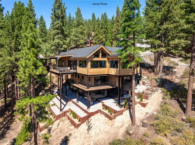 a front view of a house with a wooden deck and a forest