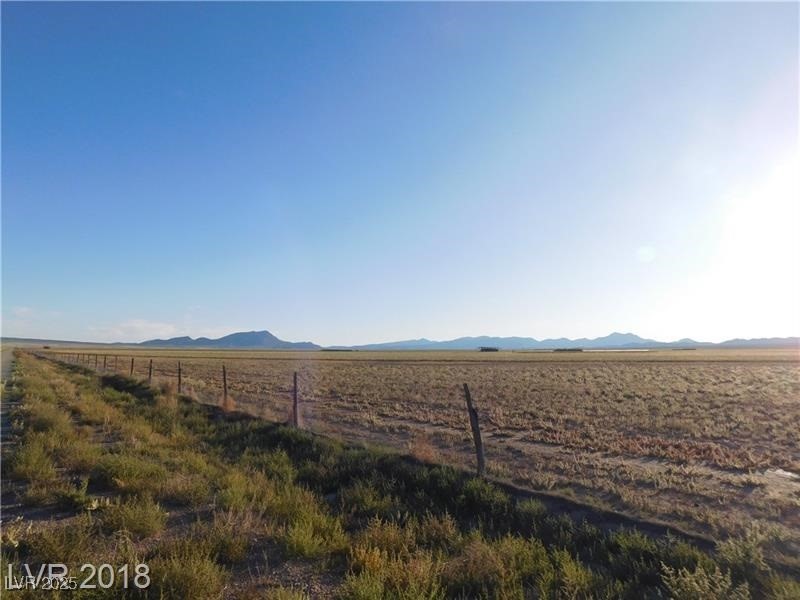 View of yard with fence, a rural view, and a mountain view