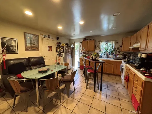 a kitchen with stainless steel appliances kitchen island granite countertop a dining table chairs and a refrigerator
