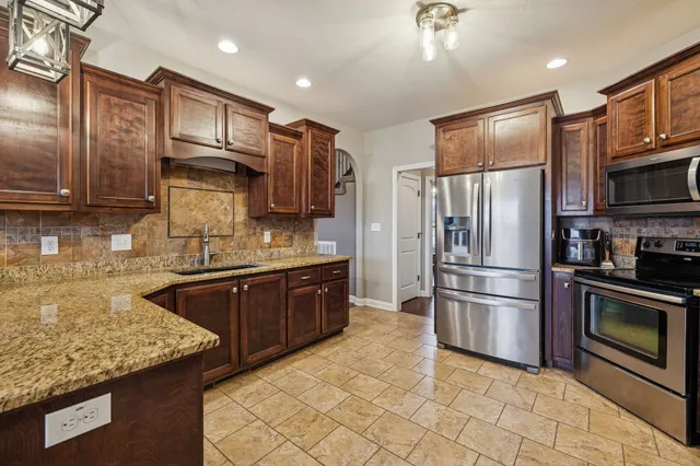a kitchen with stainless steel appliances granite countertop a refrigerator a stove a sink and a microwave