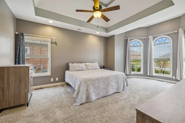 a spacious bedroom with a bed a chandelier and a dresser