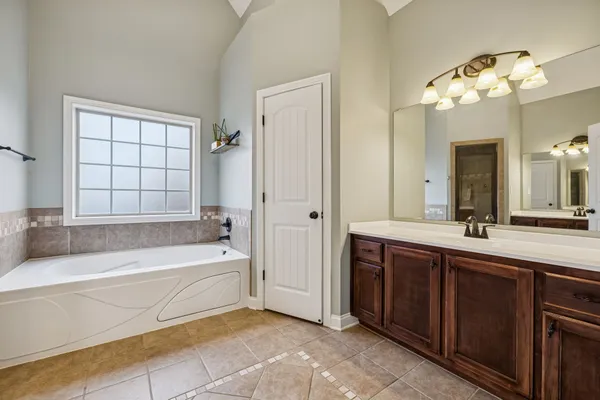 a spacious bathroom with a tub sink and mirror