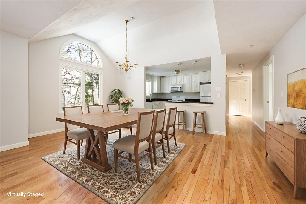 13 Pga Lane, Unit 424 Mashpee, MA 02649 - Photo 5 of 19 a dining room with wooden floor a chandelier a wooden table and chairs