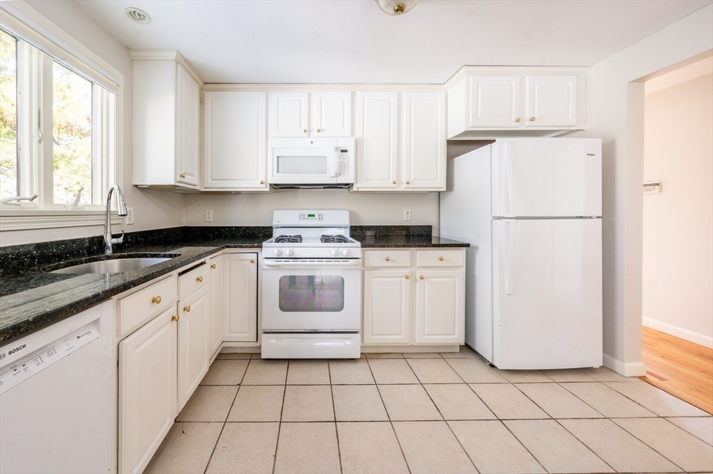 13 Pga Lane, Unit 424 Mashpee, MA 02649 - Photo 8 of 19 a kitchen with white cabinets and white appliances