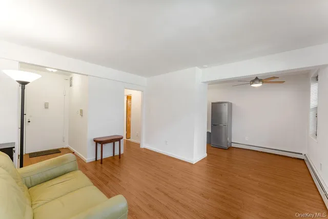 a view of an empty room and wooden floor and a bathroom