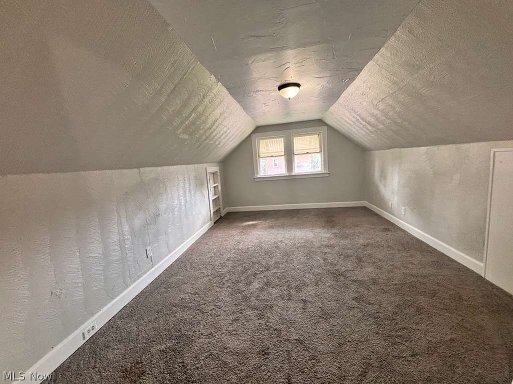 907 Rondel Road Cleveland, OH 44110 - Photo 21 of 26 Spacious attic room featuring sloped ceilings, wall-to-wall carpeting, a built-in shelving unit, and a window providing natural illumination