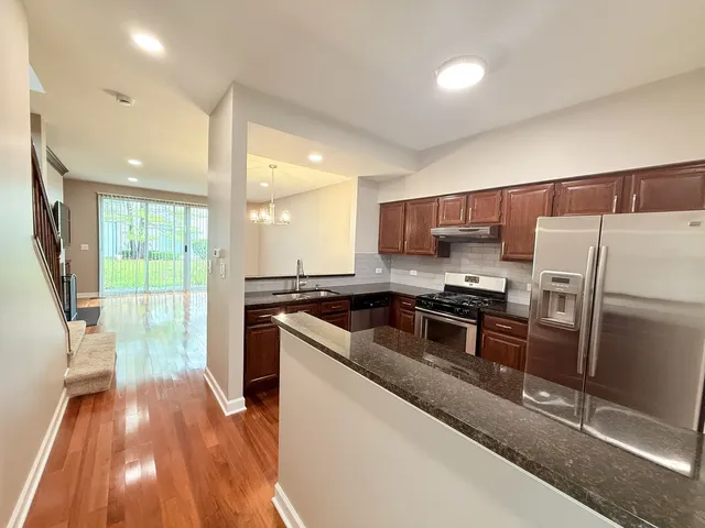 a kitchen with a refrigerator a sink dishwasher with a stove and wooden floor