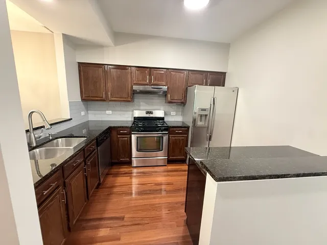 a kitchen with stainless steel appliances granite countertop a sink stove and refrigerator