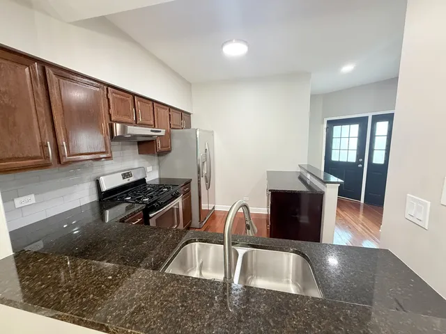 a kitchen with stainless steel appliances granite countertop a sink stove and refrigerator