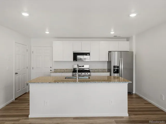 a kitchen with stainless steel appliances granite countertop a sink a stove and a refrigerator