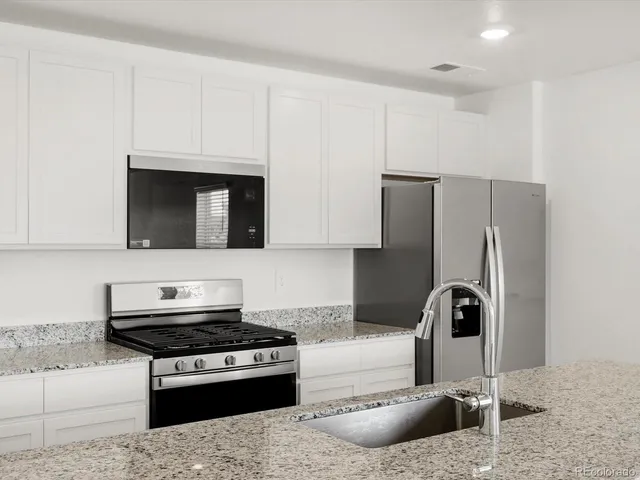 a kitchen with stainless steel appliances granite countertop a refrigerator and a stove top oven