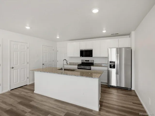 a kitchen with kitchen island a sink stainless steel appliances and white cabinets