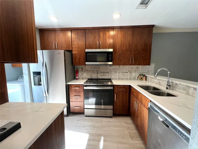 a kitchen with stainless steel appliances wooden cabinets and a stove top oven
