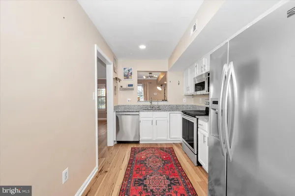 a kitchen with granite countertop stainless steel appliances a sink and refrigerator