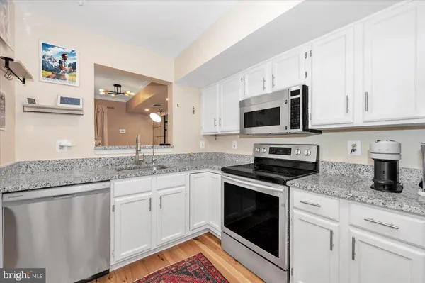 a kitchen with granite countertop white cabinets and white appliances