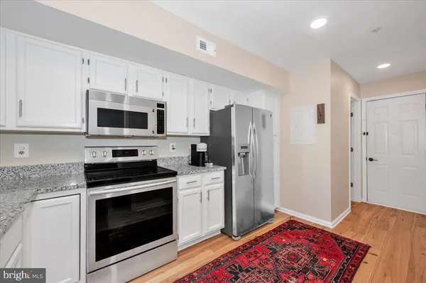 a kitchen with stainless steel appliances kitchen island granite countertop a refrigerator stove and white cabinets