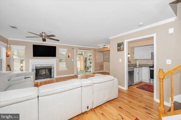 a living room with stainless steel appliances furniture a fireplace and a flat screen tv