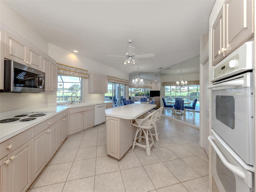 1684 Valley Drive Venice, FL 34292 - Photo 11 of 58 a kitchen with stainless steel appliances kitchen island granite countertop a sink a stove a microwave a dining table and chairs