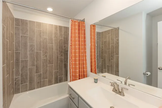 a bathroom with a granite countertop sink and a bathtub